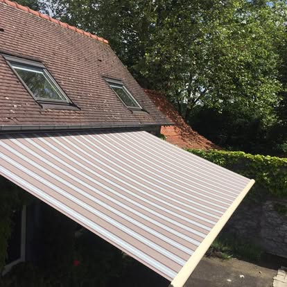 Store banne raye beige et blanc installe sur facade de maison